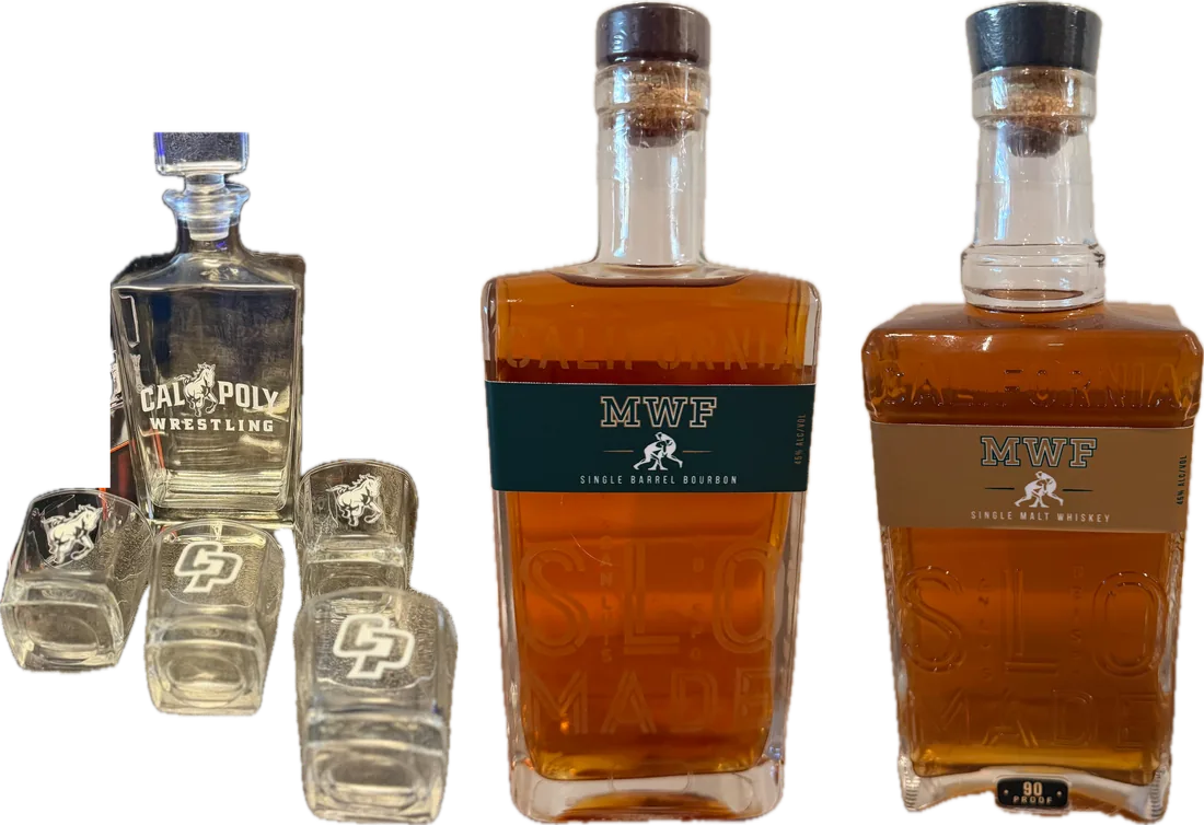 The Cal Poly whiskey set: an engraved decanter and four rocks glasses beside two SLO Stills whiskeys with Mustang Wrestling Foundation labels